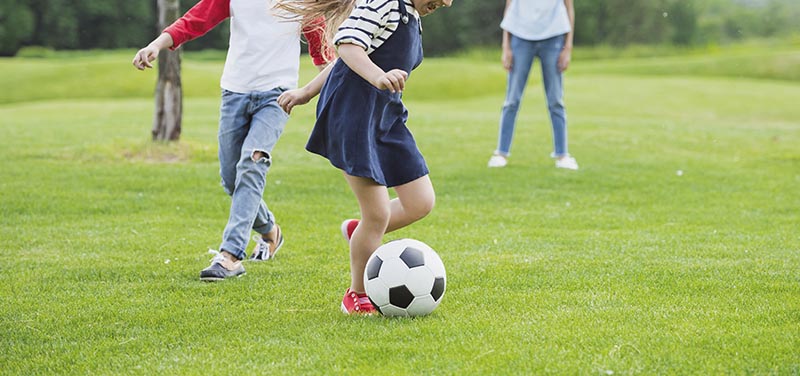 Dos niños jugando al fútbol en césped artificial
