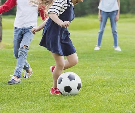 Dos niños jugando al fútbol en césped artificial