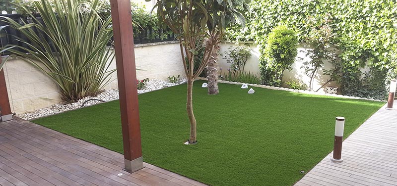 Instalación de césped artificial con tarima de madera en un jardín