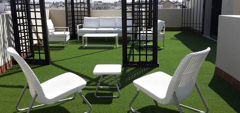 Terraza con césped artificial y muebles modernos